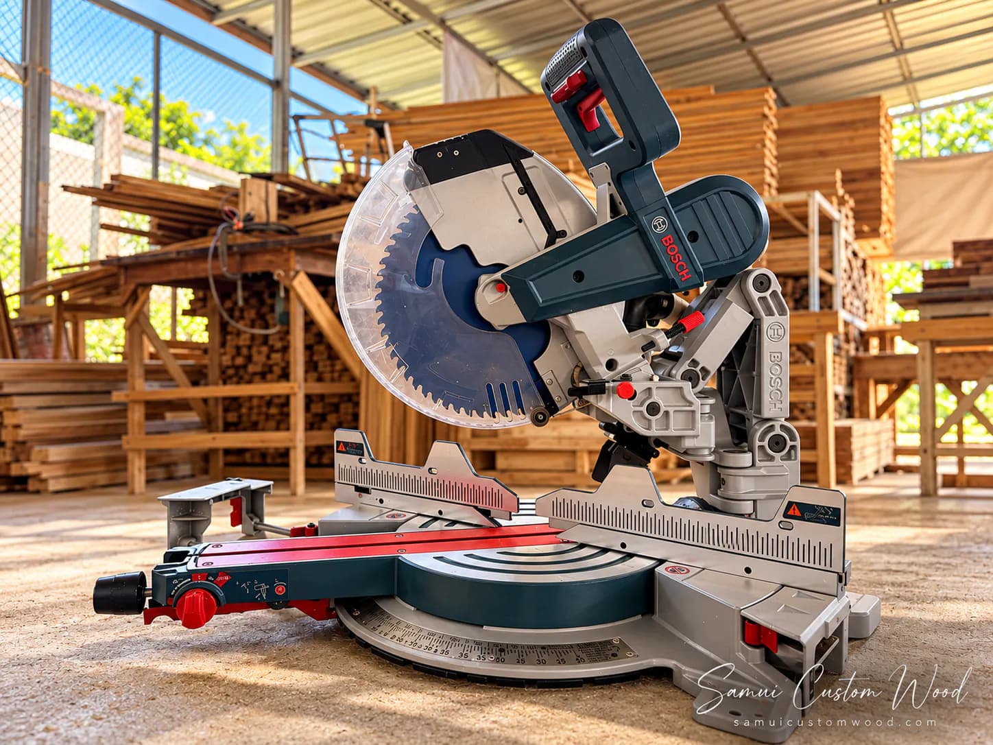A sliding mitre saw on the workshop floor in front of the timber racks